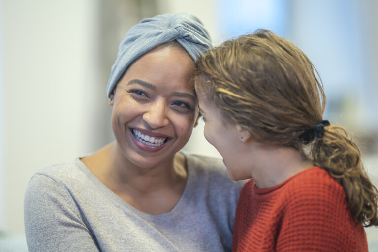 Smiling woman with cancer embracing her daughter