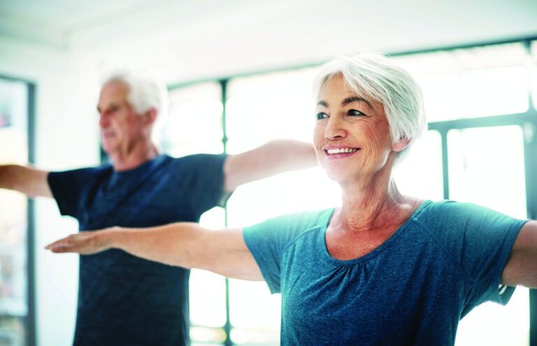 Elderly man and woman smiling doing yoga