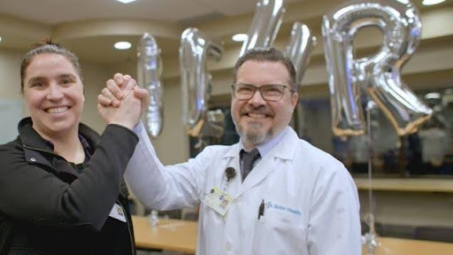 Two medical professionals holding hands and raising them up in cheer